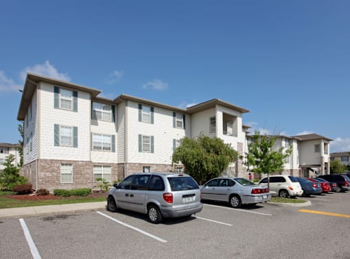A parking lot with cars and apartment buildings in the background.at Valencia Trace, ORLANDO, FL 32825