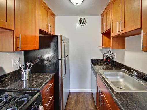 The Post Apartments kitchen with dark wood cabinets and stainless steel appliances