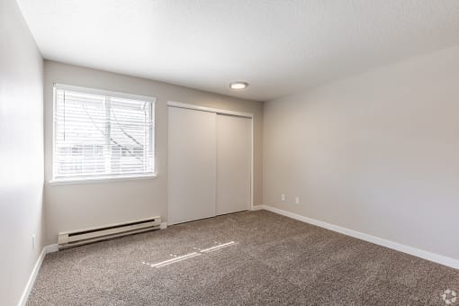 2 BR Apartments in Portland OR - Township Eastside - Empty Bedroom with Wall-to-wall Carpet, Window, and Closet at Township Eastside, Portland