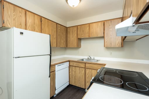 Apartments in Gresham, OR- Township Eastside- Wood-Style Cabinets with Electric Stove and White Refrigerator at Township Eastside, Portland