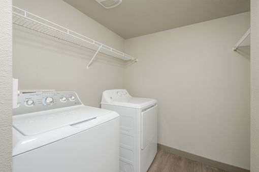 A white dryer and washer are in a small laundry room at VISTA CREEK Apartments, Laughlin, NV 89029
