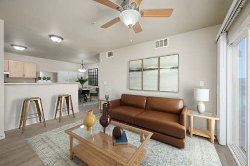 A living room with a brown couch, a ceiling fan, and a coffee table at VISTA CREEK Apartments, Laughlin, 89029