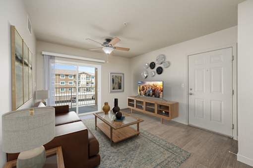 A living room with a brown couch, a wooden coffee table, and a ceiling fan at VISTA CREEK Apartments, Laughlin Nevada