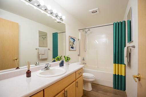 A bathroom with a white counter top and a green shower curtain.at Vancouver Mall Apartments, Vancouver ? 