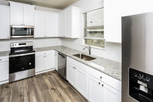 A modern kitchen with white cabinets and a stainless steel refrigerator.