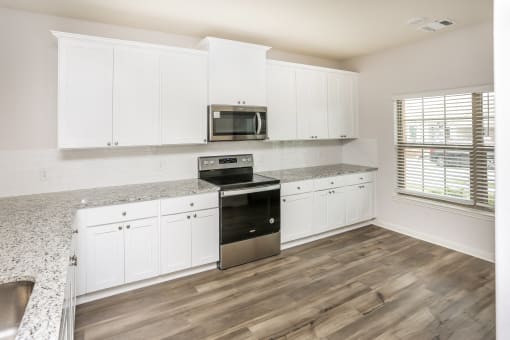 A kitchen with white cabinets and a granite countertop.