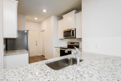  4 Bedroom single family homes for rent in fort Worth, TX- Oak Ridge - An interior shot of the kitchen, featuring stainless steel appliances, white cabinetry, and granite countertops