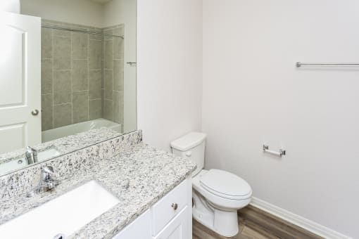 A white toilet sits next to a marble sink in a bathroom.