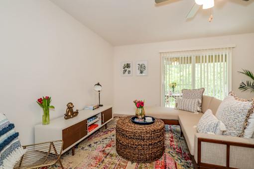 A living room with a white couch, a wicker coffee table, and a ceiling fan.