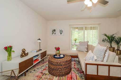 A living room with a white couch, a wicker coffee table, and a ceiling fan.