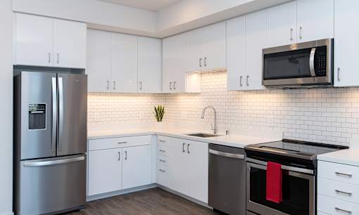 A modern kitchen with white cabinets and a stainless steel refrigerator.