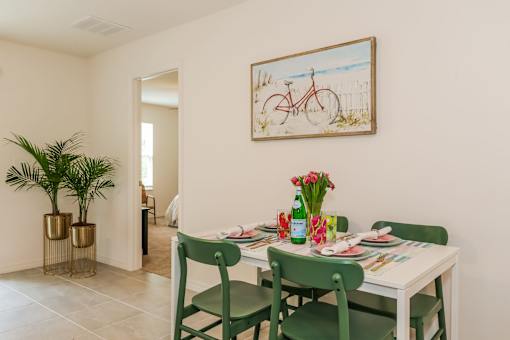 A dining room with a white table and green chairs.