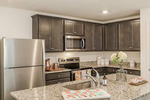 A kitchen with a granite countertop and a stainless steel refrigerator.