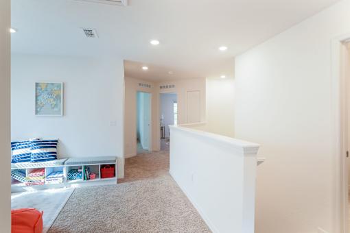 A room with a white wall and a painting hanging on it.
