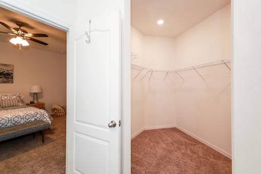 A bedroom with a bed, pillows, a ceiling fan, and a wall-mounted shelf.
