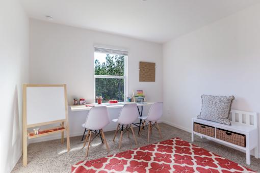 A white room with a red rug and a white table with chairs.