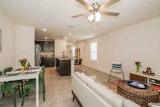 A well-lit, modern kitchen and dining area with a white ceiling fan.