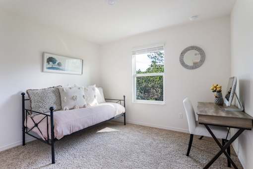A bedroom with a bed, desk, and window.