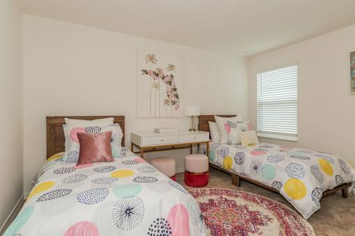 A bedroom with two beds and a desk.