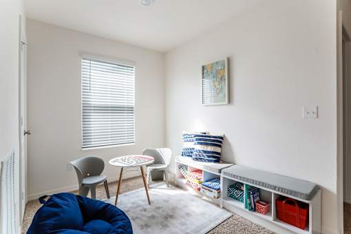 A room with a blue bean bag chair and a white chair with a small table between them.