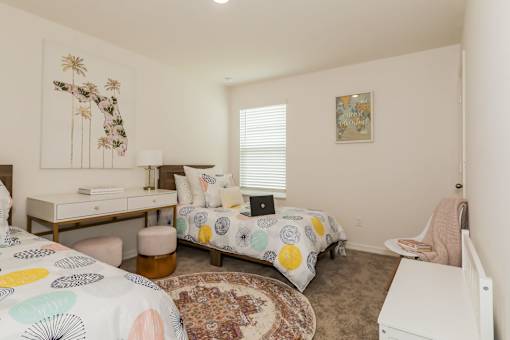 A bedroom with a bed, desk, and chair.