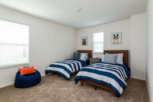 Two twin beds with blue and white striped bedspreads in a room with two blue bean bag chairs.