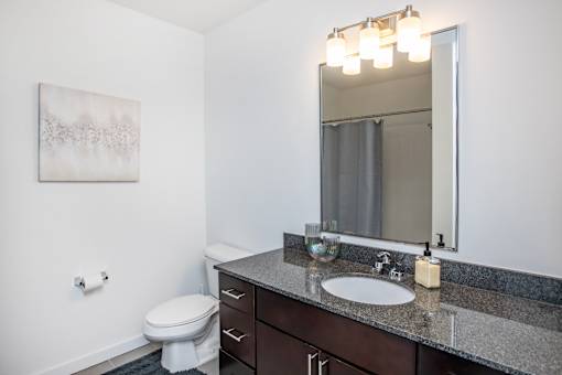 A bathroom with a toilet, sink, and mirror.