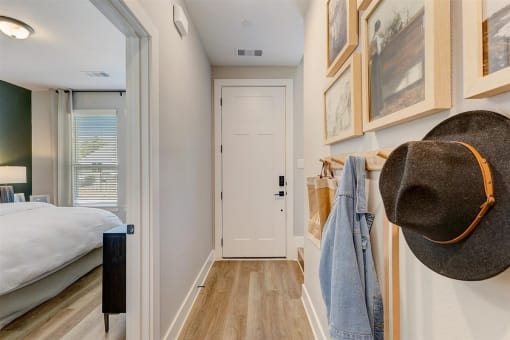 a hallway with a white door and a bed in the background