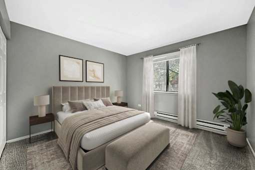 A bedroom with a large bed and a potted plant.