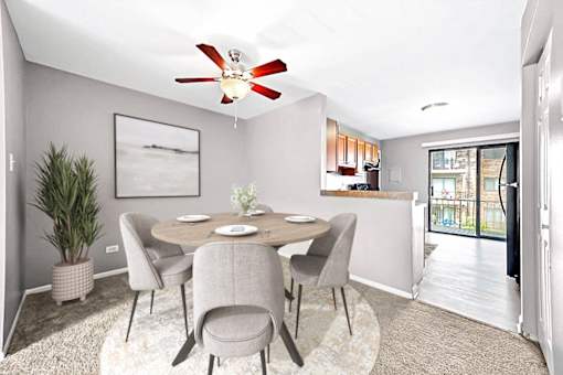 A dining room with a table set for two and a potted plant.