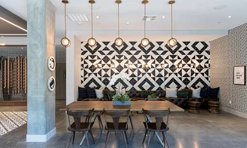 A dining room with a black and white geometric wallpaper and a grey column.