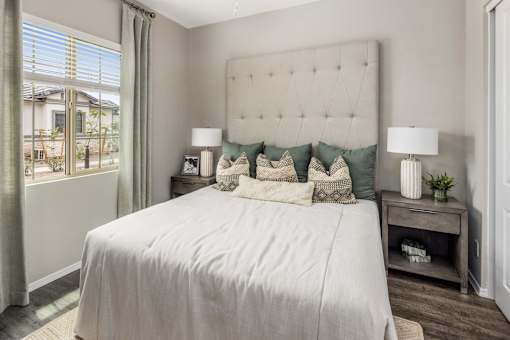A bedroom with a large bed and a window with curtains.