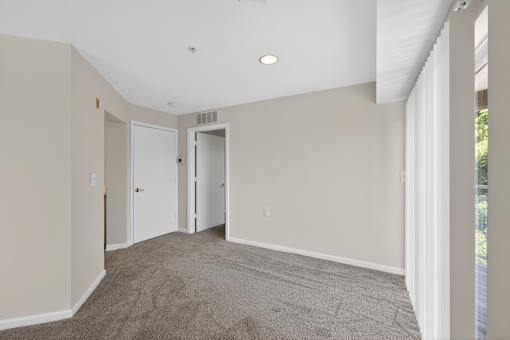 A room with a carpeted floor and two doors.