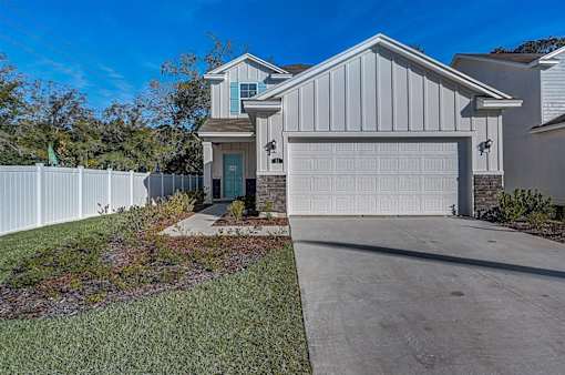 a home with a white fence and blue sky in the background