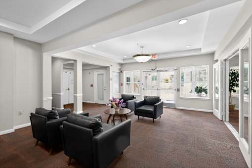 A spacious living room with black leather chairs and a wooden coffee table.