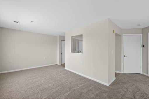 A room with a carpeted floor and a door on the right side.