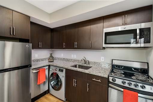 A modern kitchen with a stainless steel refrigerator, microwave, and oven.