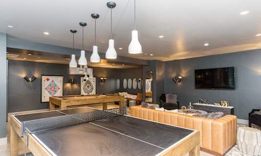 A ping pong table is in the middle of a room with a grey wall and a white ceiling.