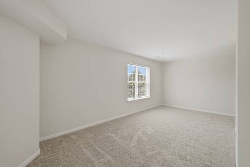 A room with a carpeted floor and a window.