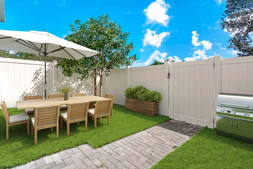 a backyard patio with a table and chairs and a grill