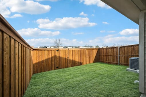 A backyard with a wooden fence and a green lawn.