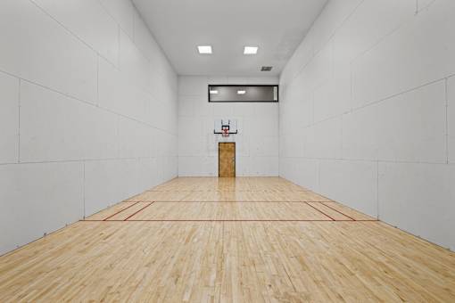 A squash court with a wooden floor and a net.