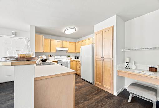 A kitchen with white appliances and wooden cabinets.