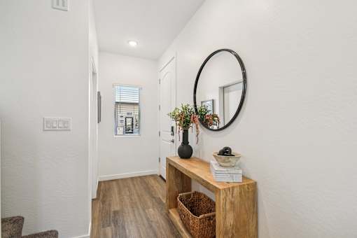 A hallway with a round mirror and a wooden bench.