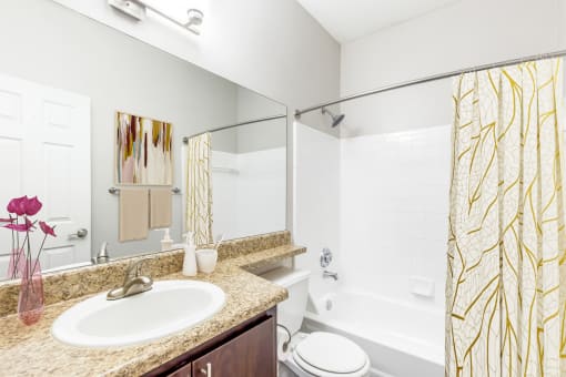 One K Apartments in Atlanta, GA photo of a bathroom with a sink and a shower and a toilet