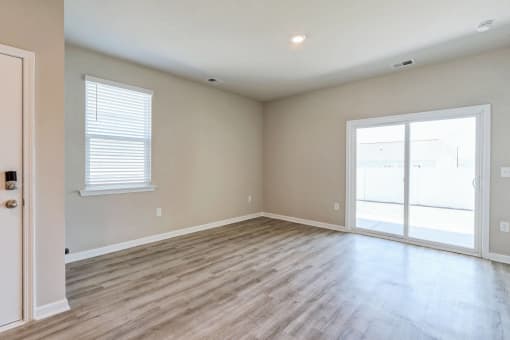 an empty living room with wood floors and a glass door