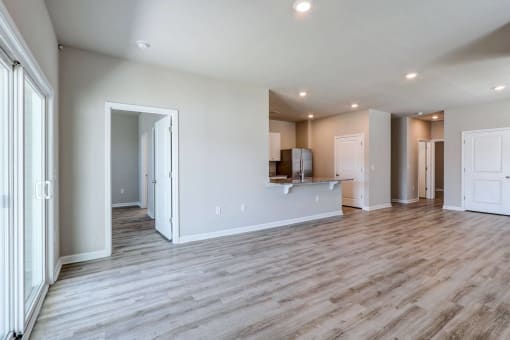 the living room and kitchen of a new home with white walls and wood flooring