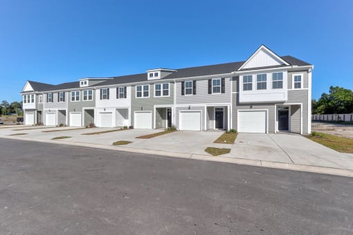 Townhomes for Rent in North Charleston, SC - Highland Townhomes - Street View of Townhomes with White and Grey Walls, Garages, and Spacious Concrete Driveways.