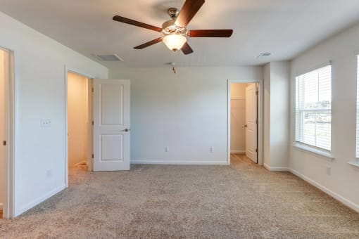 an empty living room with a ceiling fan and window