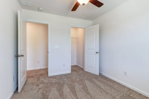 a bedroom with two closets and a ceiling fan